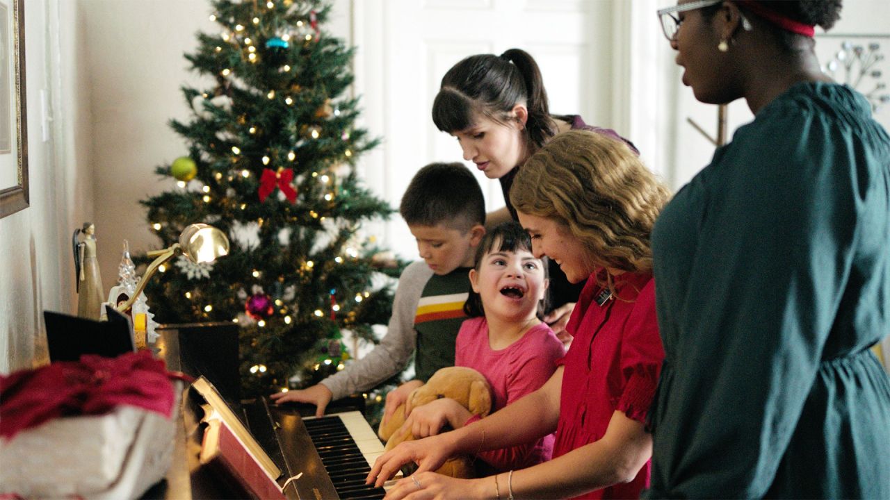 Un par de misioneras tocan el piano con una familia