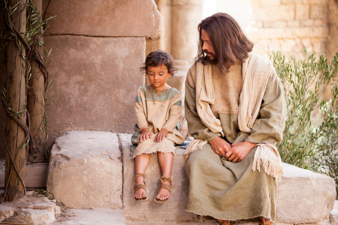 Jesús sentado junto a un niño pequeño