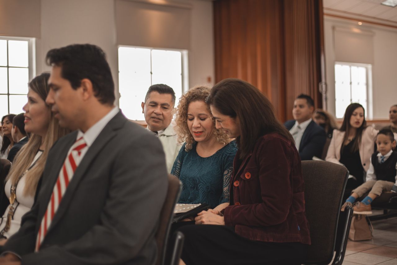 Un grupo de miembros adorando juntos en un servicio dominical