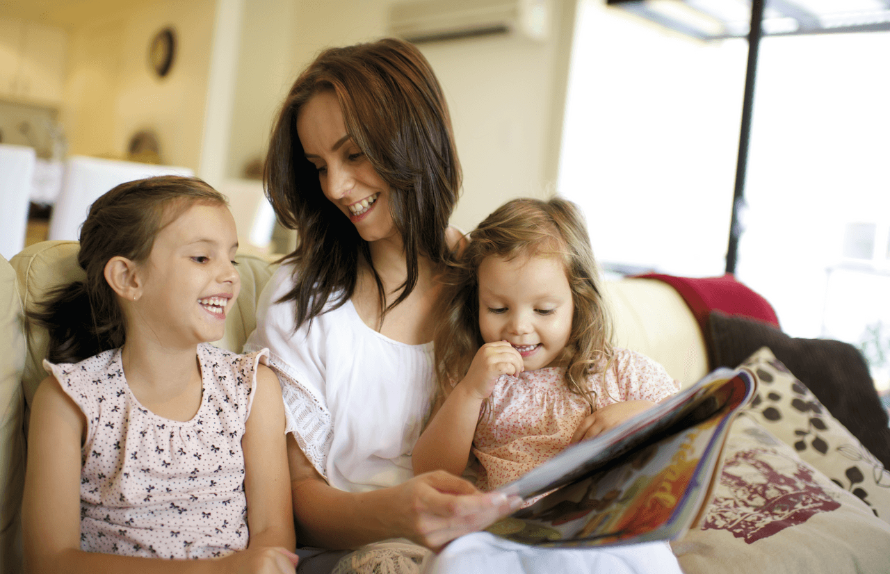 Una madre se sienta con su hijas pequeñas mientras les enseña sobre el Evangelio