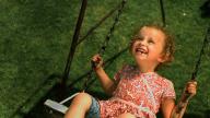 Una niña pequeña disfruta de columpiarse en un parque