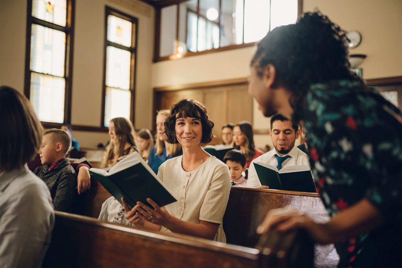Dos mujeres se sientan juntas en la Iglesia y cantan himnos