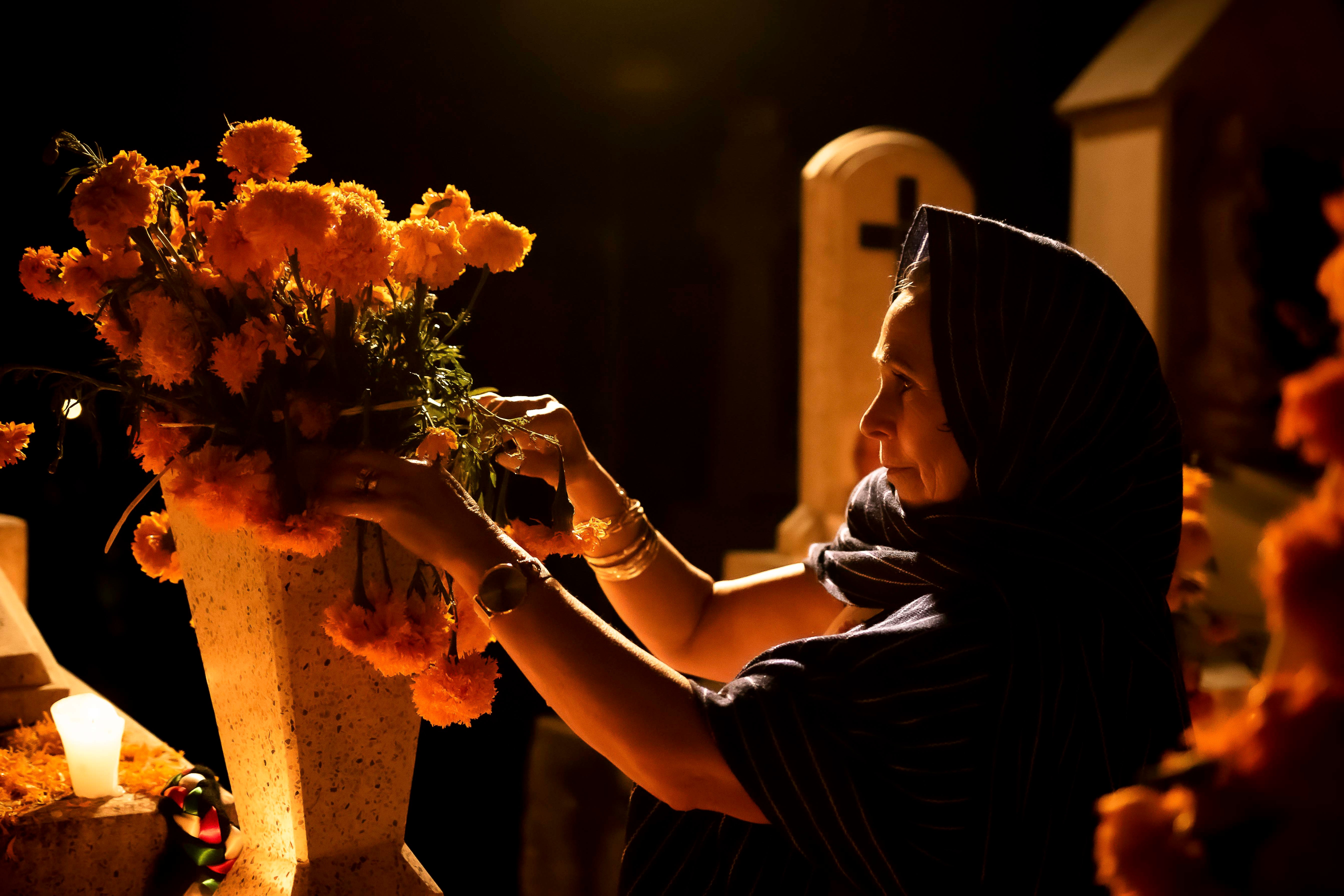 Una mujer arregla flores para el Día de los Muertos