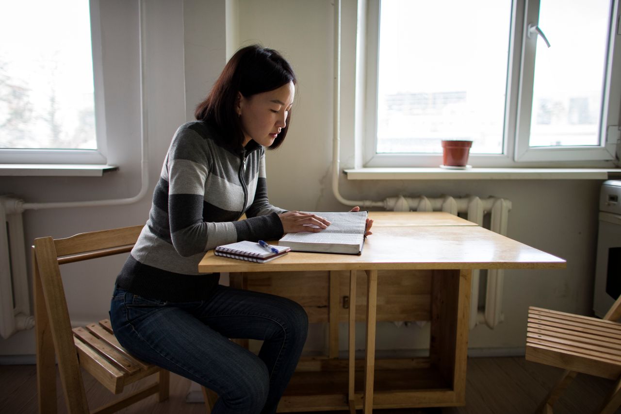Una mujer estudia el Libro de Mormón en la mesa de la cocina