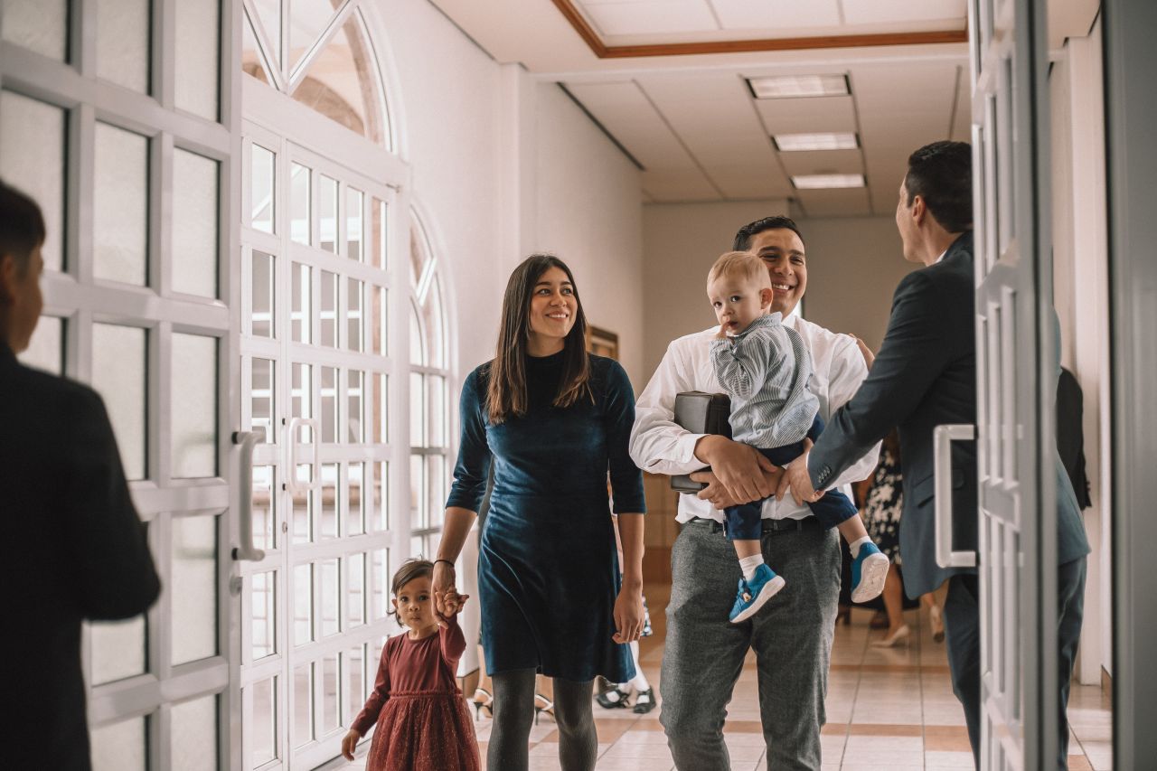 Una familia joven entra en un edificio de la Iglesia para aprender sobre el evangelio de Jesucristo