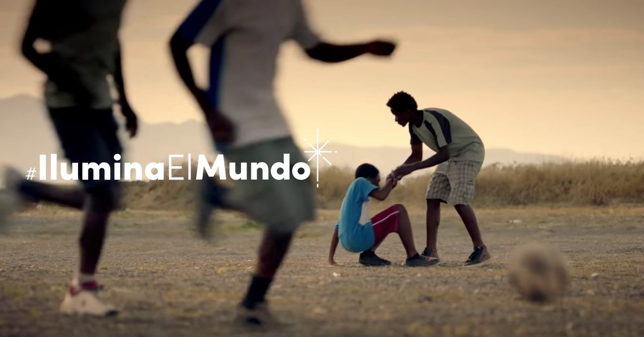 Un niño ayuda a otro niño a levantarse después de haberse caído jugando fútbol