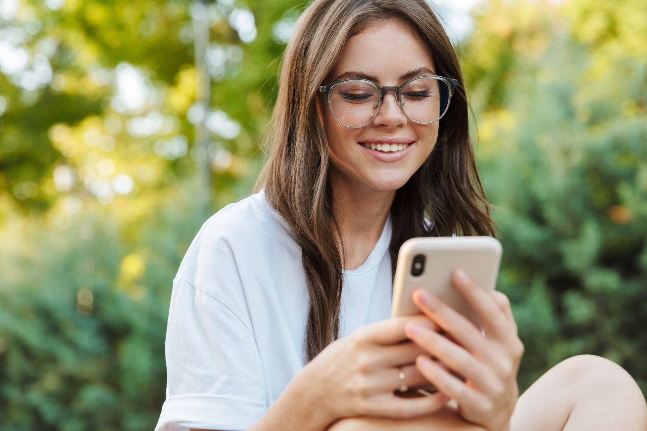 Una mujer joven que sostiene un teléfono inteligente lee sobre el evangelio de Jesucristo