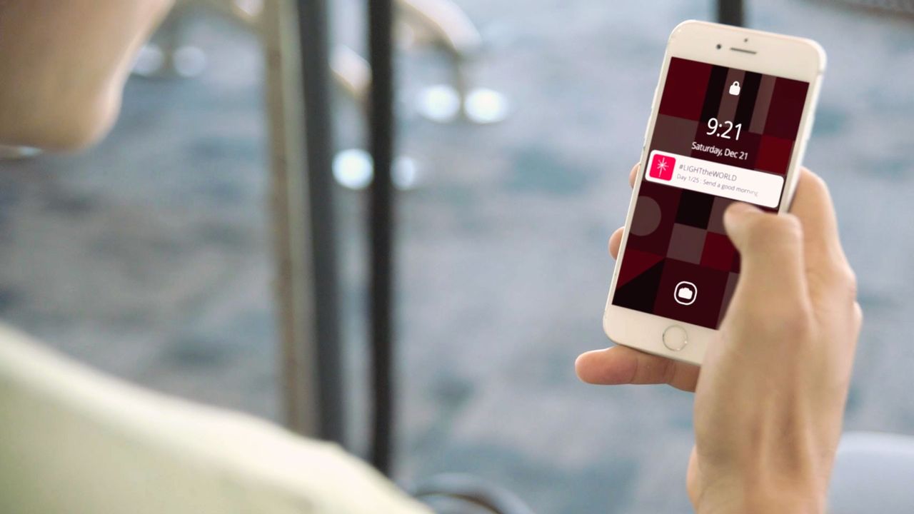 Un hombre recibe una notificación de Ilumina el Mundo en su teléfono inteligente
