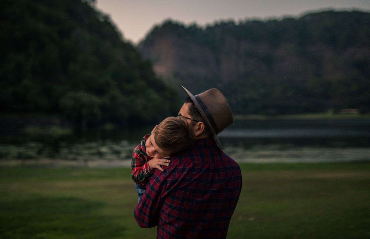 A father holds his young son while out in nature