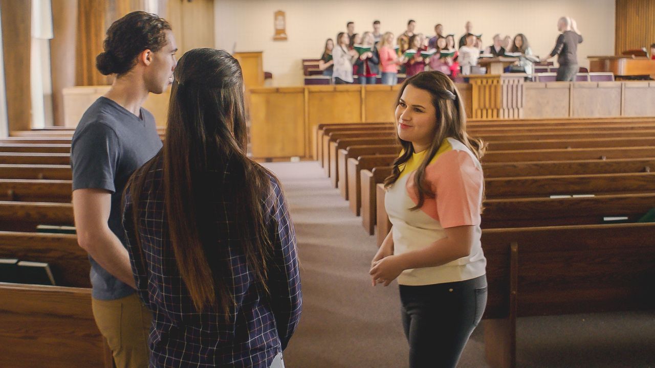 A woman gives a married couple a tour of the church building