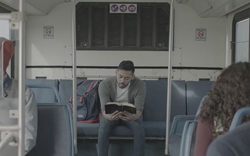 Hombre sentado en un autobús leyendo las escrituras